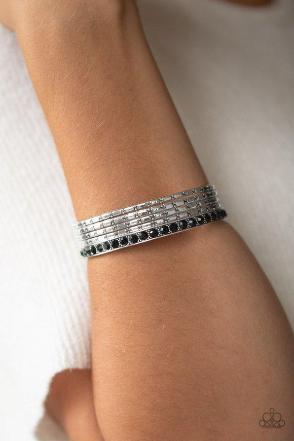 Paparazzi Glitzy Grunge - Black A single black rhinestone encrusted bangle joins four textured silver bangles, creating an edgy stack of shimmer across the wrist.
