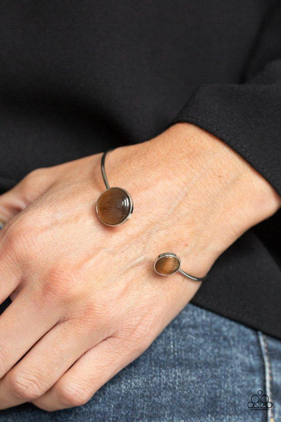 Paparazzi Brilliantly Basic - Brown  -  Featuring glowing brown cat's eye stone fittings, a wire-like silver bar curls around the wrist, creating a dainty cuff.
