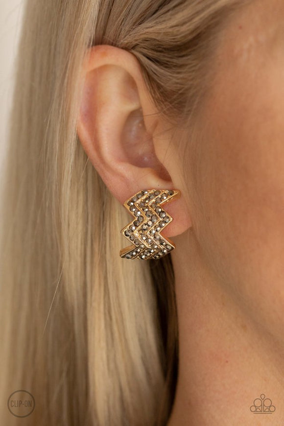 Paparazzi Fast as Lightning - Gold - Earrings  -  Row after row of glittery hematite rhinestones are encrusted along a zagging gold frame for an edgy glamour. Earring attaches to a standard clip-on earrings.
