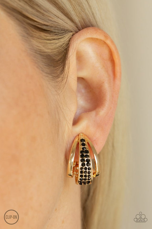 Paparazzi Bank Night - Gold - Earrings  -  The center of an abstract gold frame is encrusted in rows of glittery black rhinestones, creating an edgy frame. Earring attaches to a standard clip-on fitting.
