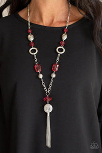 Paparazzi Ever Enchanting - Red A collection of glassy red crystal-like beads, shimmery silver hoops, and ornate silver beads link across the chest. A shimmery silver tassel streams from the bottom of a whimsical compilation for an enchanting finish. Features an adjustable clasp closure.
