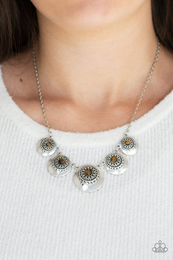 Paparazzi Solar Beam - Brown - Necklace  -  Dotted with glassy tiger's eye stone centers, silver sunburst studded frames link below the collar, creating a colorful fringe. Features an adjustable clasp closure.
