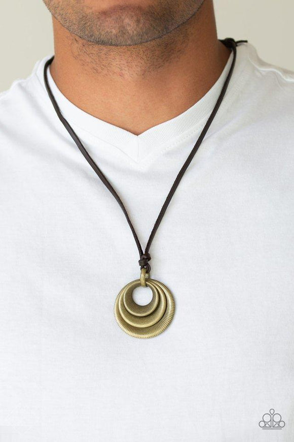 Paparazzi Desert Spiral - Brass  -  Textured and smooth beveled brass rings are knotted in place at the bottom of a brown leather cord, creating a rustic pendant. Features an adjustable sliding knot closure.
