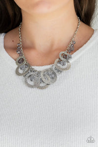 Paparazzi Turn It Up - Silver - Necklace  -  A collection of smoky crystal-like beads and hammered silver hoops dangle from the bottom of a shimmery silver chain, creating a noise-making fringe. Features an adjustable clasp closure.
