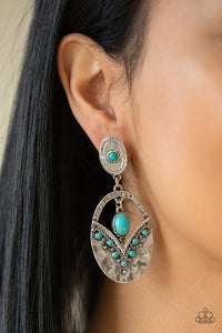 Paparazzi Terra Tribute - Blue - Earrings  -  Rippling with hammered silver textures, a turquoise stone dotted frame swings from the bottom of an ornate oval frame dotted with a matching turquoise stone. A smooth turquoise stone swings from the top of the ornate frame, creating an earthy lure. Earring attaches to a standard post fitting.
