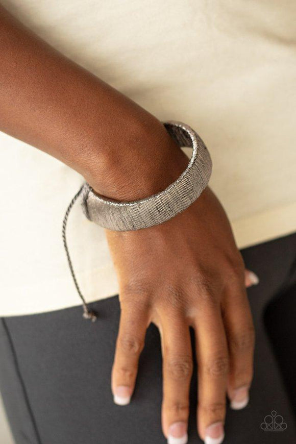 Paparazzi In a Flash - Black  -  Brushed in a metallic-like finish, shimmery wire wraps around a thick black leather band for an edgy look around the wrist. Features an adjustable sliding knot closure.
