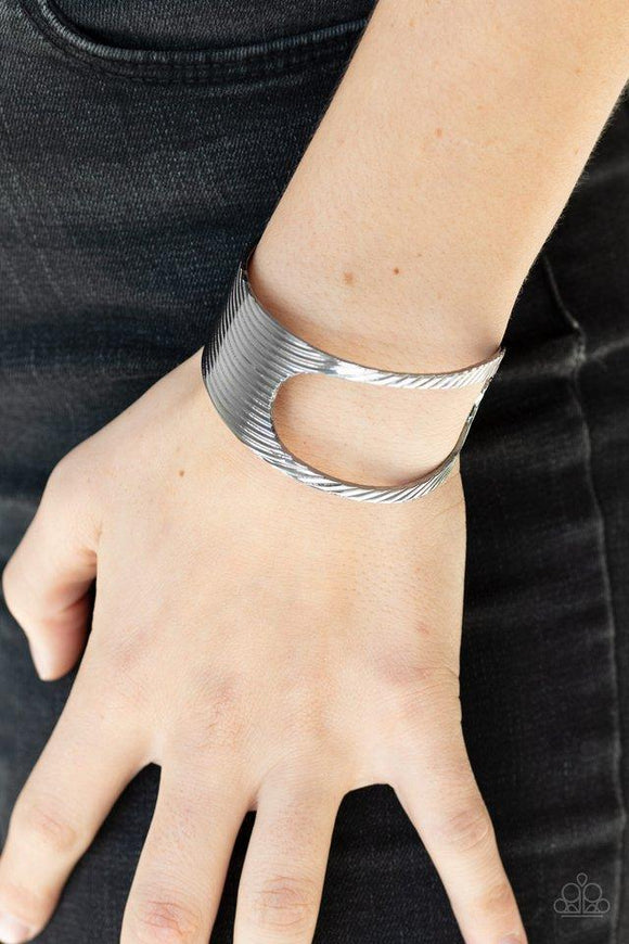 Paparazzi What GLEAMS Are Made Of - Black  -  Stamped in a slanted linear pattern, a glistening gunmetal cuff featuring an airy asymmetrical cutout wraps around the cuff for a bold industrial look.

