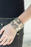 Paparazzi Serpent Shimmer - Silver  -  Featuring a shiny gold and black python print, a thick gray leather band wraps around the wrist for a wild shimmer. Features an adjustable snap closure.
