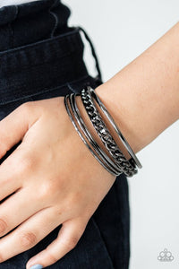 Paparazzi A Piece of The Action - Black - Bracelet  -  Pairs of smooth and textured gunmetal bangles join an antiqued bangle around the wrist that is decorated in a single strand of gunmetal chain for a gritty finish.
