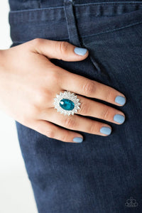 Paparazzi Secret Garden Glow - Blue - Ring  -  Dotted in dainty white rhinestones, glittery silver petals bloom from a faceted blue gem center, creating a refined centerpiece atop the finger. Features a stretchy band for a flexible fit.
