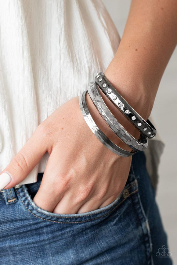 Paparazzi Revved Up Rhinestones - Multi - Bracelet
A mismatched stack of gunmetal and silver bangles are hammered in texture, creating light-catching edges that reflect an immense amount of shine. One bangle is lined with glassy white rhinestones, adding a hint of twinkle.