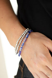 Paparazzi Elegant Essence - Blue - Bracelet  -  A pair of faceted silver beaded bracelets join a strand of glassy blue emerald style beads around the wrist, creating iridescently stretchy layers.
