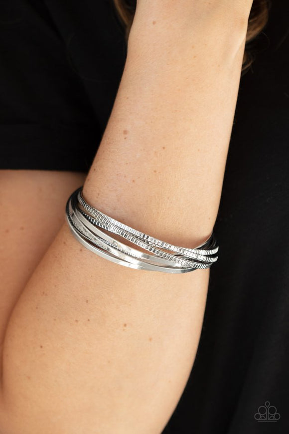 Paparazzi Trending in Tread - Silver - Bracelet  -  A set of four plain silver bangles interlocks with four silver bangles etched in a tread-like pattern, creating an edgy stacked look around the wrist.
