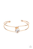 Paparazzi GLOW No Mercy - Gold - Bracelet   -  A dramatically oversized white rhinestone is fitted in place atop the center of a gold wire cuff, creating a jaw-dropping display around the wrist.
