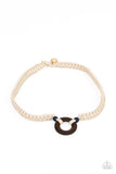 Paparazzi The MAINLAND Event - Blue - Necklace  -  A wooden hoop is knotted in place between two glassy blue beads along braided white cording around the neck for an earthy look. Features a button loop closure.
