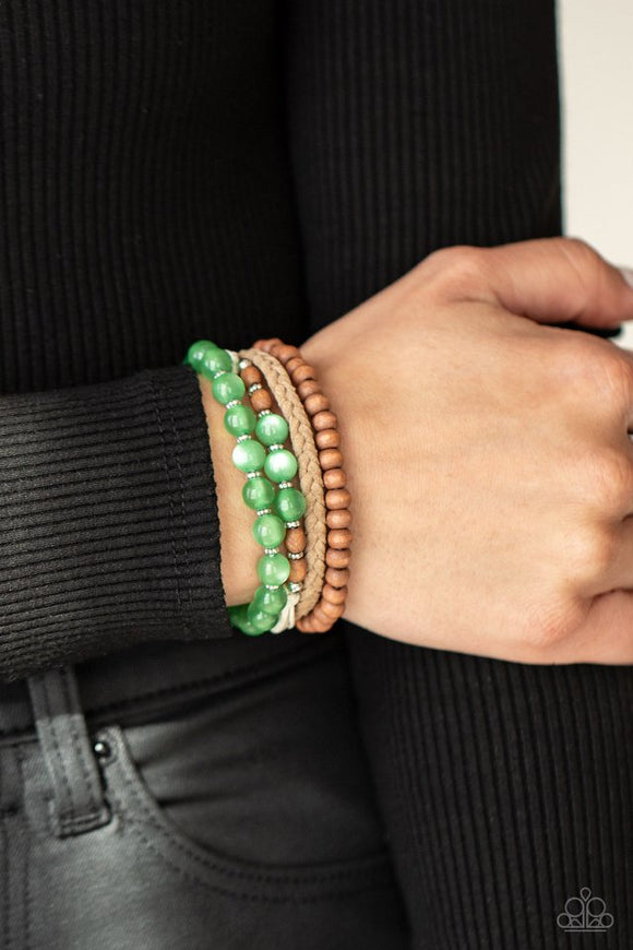 Paparazzi Down HOMESPUN - Green - Bracelet  -  Strands of glassy green cat's eye beads stand out in an earthy collection of wooden beads and braided twine, giving a polished flair to the natural homespun look as it stacks up the wrist. Features an adjustable sliding knot closure.
