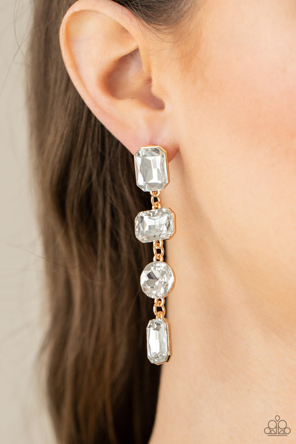 Paparazzi Cosmic Heiress - Gold - Earrings   -  A strand of oversized round, teardrop, and emerald cut white rhinestones trickles from the ear, creating a jaw-dropping golden chandelier. Earring attaches to a standard post earring.
 