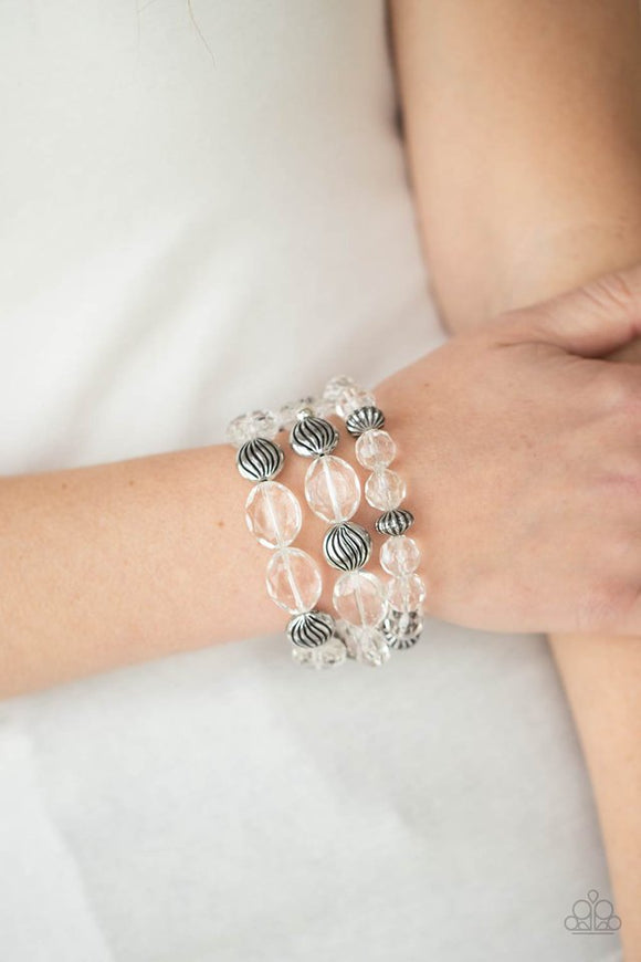 Paparazzi Crystal Charisma - White - Bracelet  -  A mismatched collection of sparkly white crystal-like beads and textured silver accents are threaded along stretchy bands around the wrist, creating glamorous layers.
