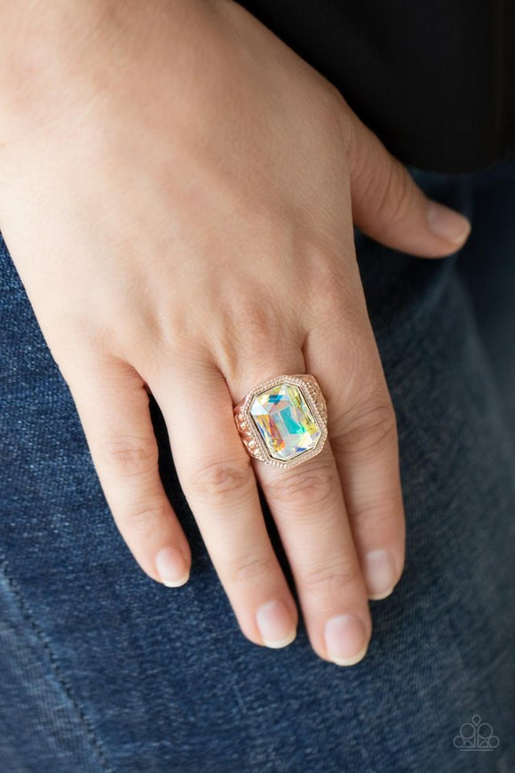Paparazzi Galaxy Goddess - Rose Gold - Ring  -  Featuring a dramatic UV shimmer, an oversized emerald cut gem is pressed into the center of a thick rose gold frame embossed in leafy patterns for a stellar statement atop the finger. Features a stretchy band for a flexible fit.
