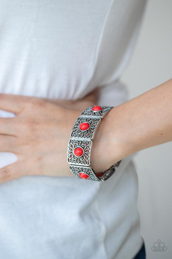 Paparazzi Cakewalk Dancing - Red - Bracelet  -  A red oval bead is pressed into the center of an airy square frame featuring whimsical heart-shaped and vine-like filigree. The patterned frames are threaded along stretchy bands to repeat around the wrist creating a charismatic ambiance.

