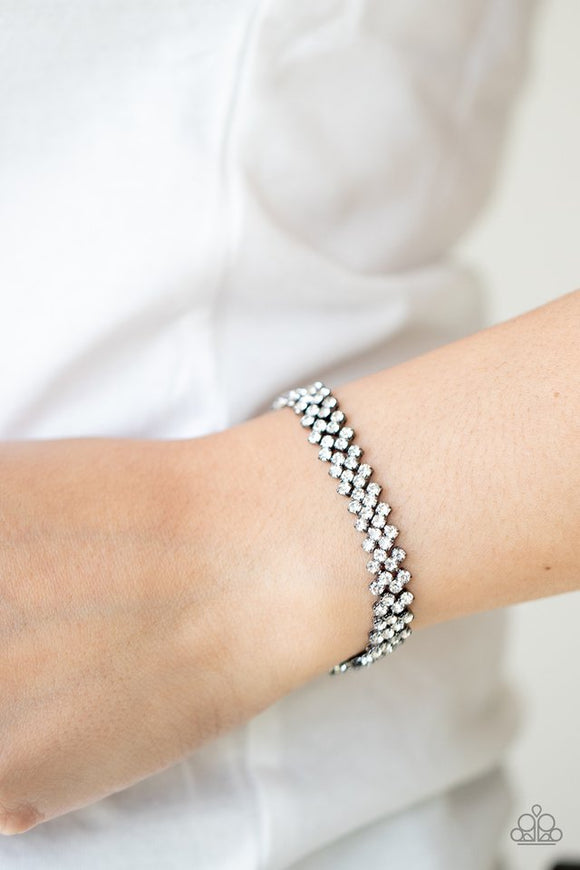 Paparazzi Chicly Candescent - Black - Bracelet  -  Featuring sleek gunmetal fittings, dainty rows of glassy white rhinestones delicately slant across the wrist, coalescing into a timeless centerpiece. Features an adjustable clasp closure.
