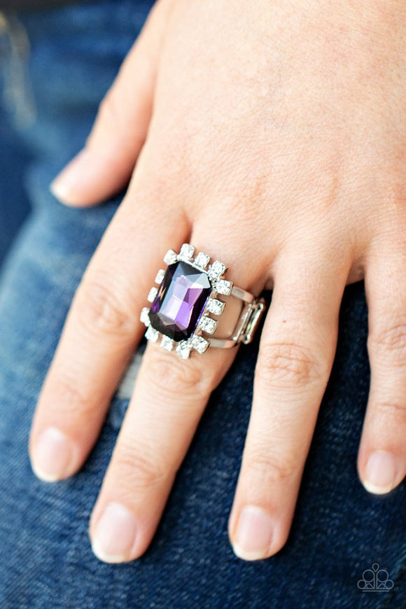 Paparazzi Galactic Glamour - Purple - Ring  -  Featuring dainty silver square fittings, an explosion of glassy white rhinestones fans out from a dramatically oversized emerald cut purple rhinestone center, creating a stellar centerpiece atop the finger. Features a stretchy band for a flexible fit.
