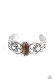Paparazzi Solar Solstice - Brown - Bracelet  - 2021 Convention Exclusive  -  An oval Tiger's eye stone is pressed into the center of a studded silver frame atop an airy silver cuff embellished in studded sun-like frames for an earthy pop of seasonal color around the wrist.
