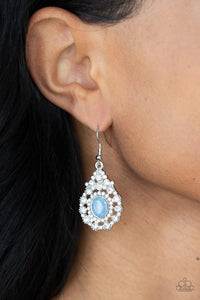 Paparazzi Celestial Charmer - Blue - Earrings  -  Bordered in a ring of dainty white rhinestones, an opalescent blue gem adorns the center of a teardrop frame radiating with glassy white rhinestones for an ethereally elegant look. Earring attaches to a standard fishhook fitting.
