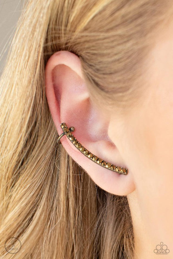 Paparazzi Give Me The SWOOP - Brass Post Earring - Earrings  -  A dainty row of glitzy aurum rhinestones is encrusted along a gritty brass bar that swoops up the ear for a smoldering style. Features a dainty cuff attached to the top for a secure fit.
