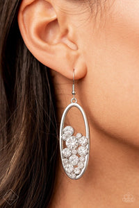 Paparazzi Prismatic Poker Face - White - Earrings  -  Effervescent stacks of brilliant white rhinestones bubble up inside a simple silver oval frame creating a prismatically stunning lure. Earring attaches to a standard fishhook fitting.

