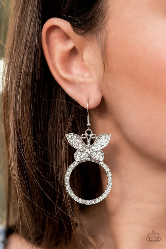 Paparazzi Paradise Found - White - Earrings  -  A white rhinestone encrusted silver butterfly flutters atop a silver ring dotted in matching white rhinestones, resulting in a dazzling statement piece. Earring attaches to a standard fishhook fitting.
