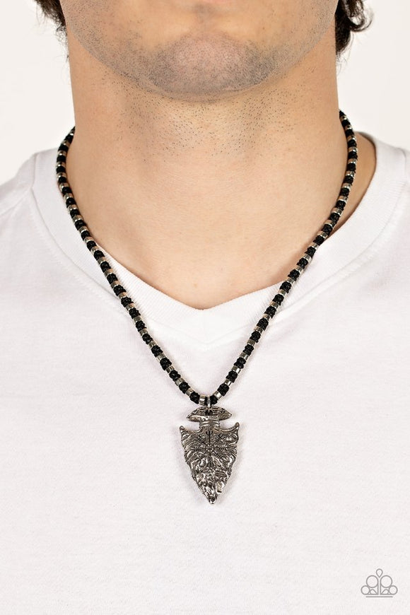 Paparazzi Get Your ARROWHEAD in the Game - Black - Necklace  -  Dainty silver accents are knotted in place along a braided black cord below the collar. Stamped and hammered in tribal inspired patterns, a rustic silver arrowhead pendant swings from the earthy display for an authentic finish. Features a button loop closure.

