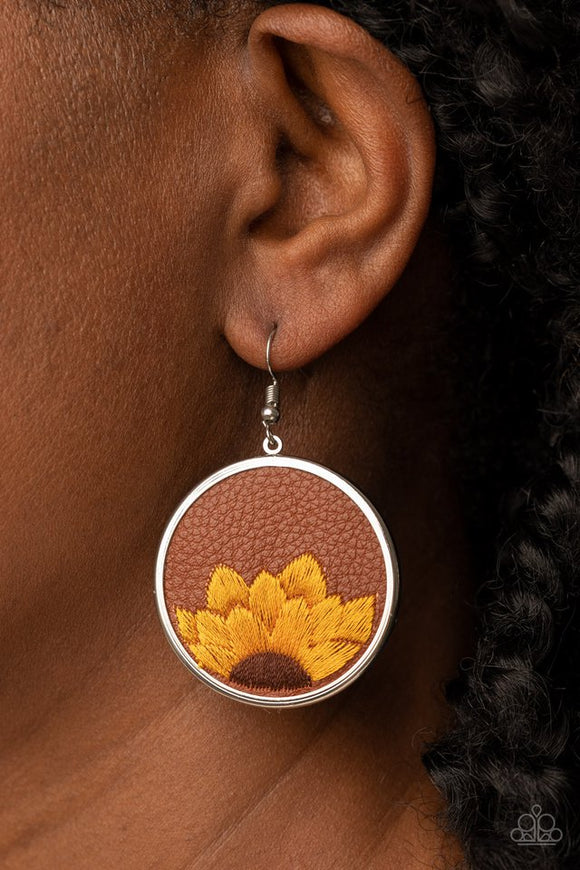 Paparazzi Sun-Kissed Sunflowers - Brown - Earrings  -  A golden yellow and brown threaded sunflower is stitched into the bottom of a brown leather frame that is encased in a sleek silver frame, resulting in a whimsical floral fashion. Earring attaches to a standard fishhook fitting.
