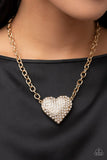 Paparazzi Heartbreakingly Blingy - Gold - Necklace  -  A dramatically oversized gold heart frame is encrusted in row after row of dazzling white rhinestones, resulting in a heart-racing sparkle below the collar. Features an adjustable clasp closure.
