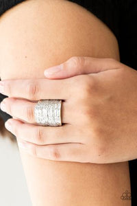 Paparazzi Paleo Patterns - Silver Radiating with patterns derived from nature, a rippling silver frame curves around the finger for a bold look. Features a stretchy band for a flexible fit.
