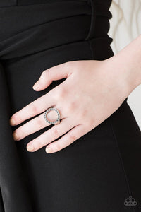 Paparazzi One-GLAM Band - Silver Encrusted in smoky rhinestones, a circular frame adorns the finger, creating a glamorous centerpiece. Features a stretchy band for a flexible fit.
