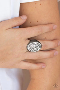 Paparazzi Bling Scene - Black
Row after row of dazzling white rhinestones radiate out from the center of a thick gunmetal frame, creating a blinding centerpiece atop the finger. Features a stretchy band for a flexible fit.
