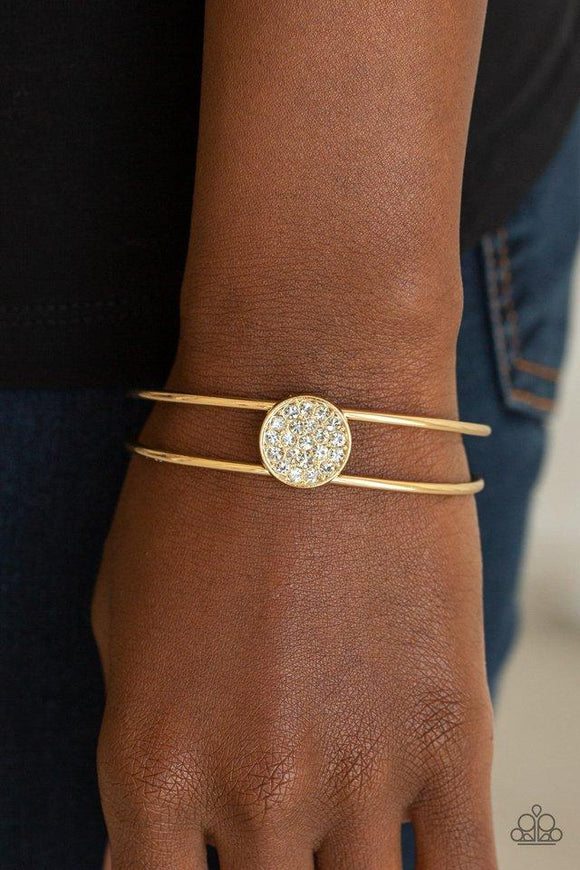 Paparazzi Dial Up The Dazzle - Gold - Bracelet
Glittery white rhinestones are encrusted along the front of a shimmery gold disc atop the center of a dainty gold cuff for a dazzling look. 