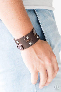 Paparazzi Downright Desperado - Brown - Bracelet
Pieces of shiny brown leather are studded together to create an edgy urban look around the wrist. Features an adjustable snap closure. 
All jewelry is Lead &amp; Nickel Free!
