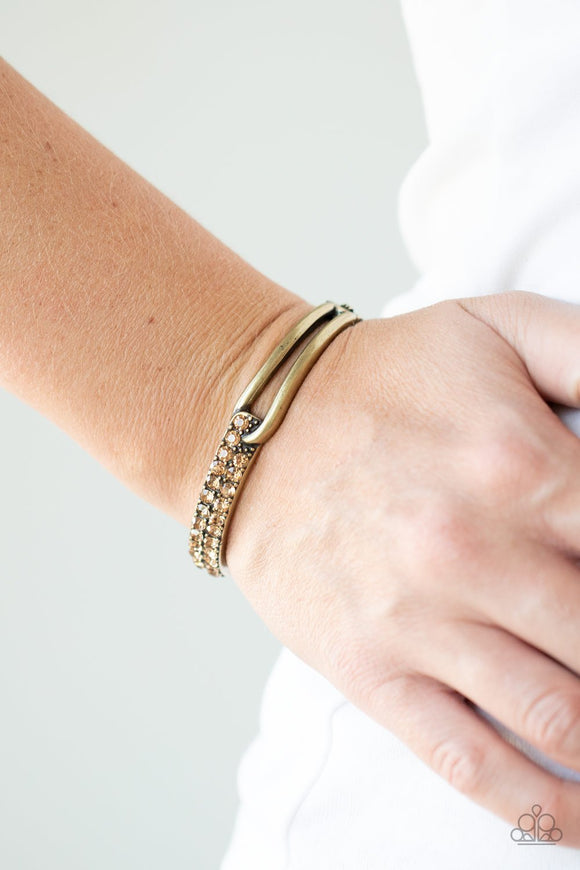 Paparazzi Freeze! - Brass - Bracelet
An airy brass fitting links with an antiqued brass band encrusted in two rows of glittery topaz rhinestones across the wrist, creating an edgy bangle-like cuff. Features a hinged closure.
