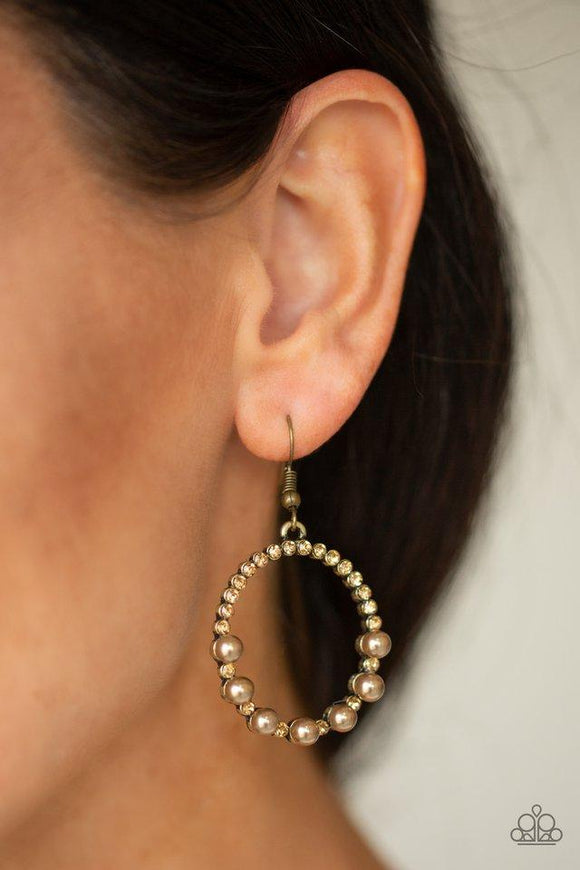 Paparazzi Glowing Grandeur - Brass - Earrings
Encrusted in golden topaz rhinestones, the bottom of a glistening brass hoop is dotted in pearly brass beads for a refined fashion. Earring attaches to a standard fishhook fitting. 