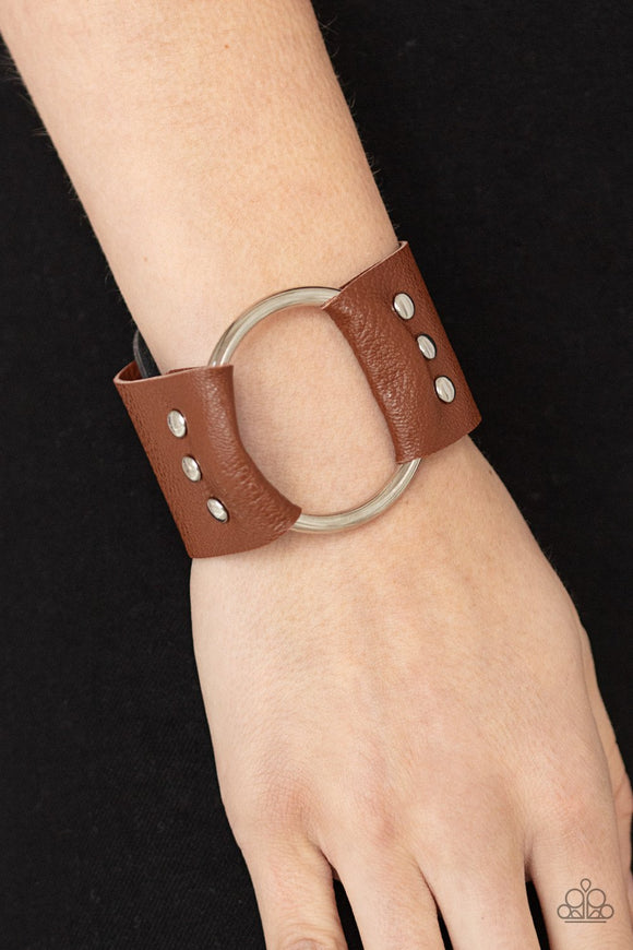Paparazzi Moto Mayhem - Brown - Bracelet
An oversized silver hoop is studded in place between the center of studded pieces of black and brown leather, creating a rustic centerpiece around the wrist. Features an adjustable snap closure.
