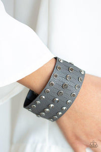 Paparazzi Now Taking The Stage - Silver - Bracelet
Pressed into sleek silver frames, glittery hematite rhinestones are studded across a thick gray leather band featuring a center lined with slits for a sassy finish. Features an adjustable snap closure. 
