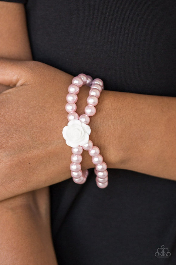 Paparazzi Posh And Posy - Pink - Bracelet
Connected by a flirty white resin rose, classic pink pearls are threaded along stretchy bands around the wrist for a vintage inspired fashion.
