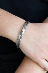 Paparazzi Power Pack - Silver - Bracelet
Stamped in geometrical tribal patterns, a dainty silver cuff curls around the wrist for a seasonal look. 