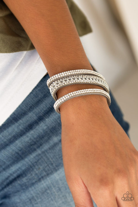 Paparazzi Rollin In Rhinestones - Silver - Bracelet
Rows of glassy white rhinestones and a shimmery silver chain are encrusted along gray suede bands for a sassy look. Features an adjustable snap closure.
