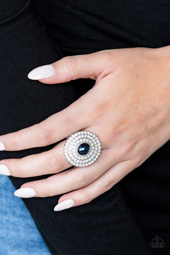 Paparazzi Royal Ranking - Blue - Ring
A pearly blue bead is pressed into the center of a round silver frame radiating with countless white rhinestones, creating a blinding statement piece. Features a stretchy band for a flexible fit.