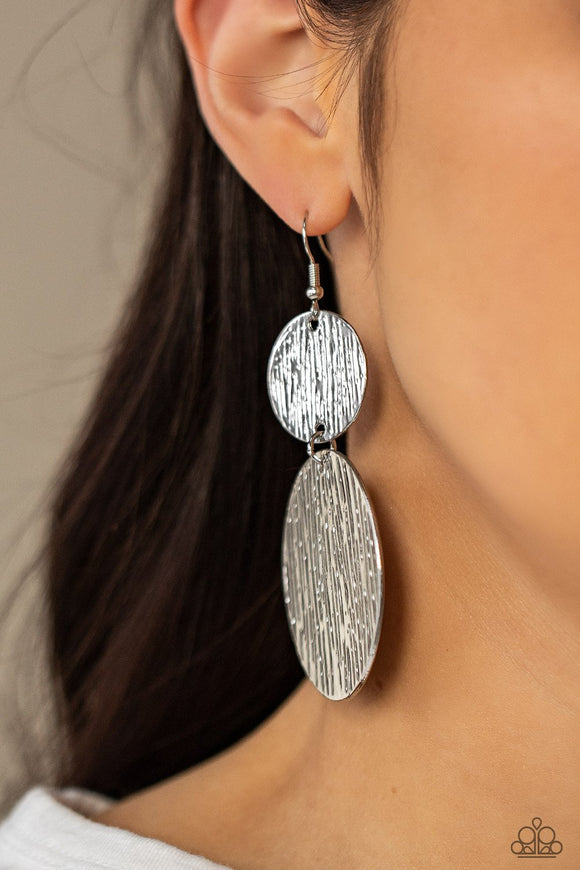 Paparazzi Status Cymbal - Silver - Earrings
Embossed in tactile linear patterns, two mismatched silver discs link into a glistening lure. Earring attaches to a standard fishhook fitting.
