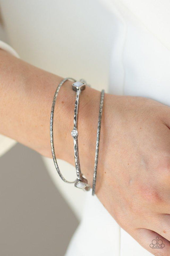 Paparazzi Sunset Fusion - Silver - Bracelet
Infused with a pair of dainty textured bangles, a hammered silver bangle is encrusted in sections of glassy white rhinestones and square Paloma beads for a seasonal blend. 
