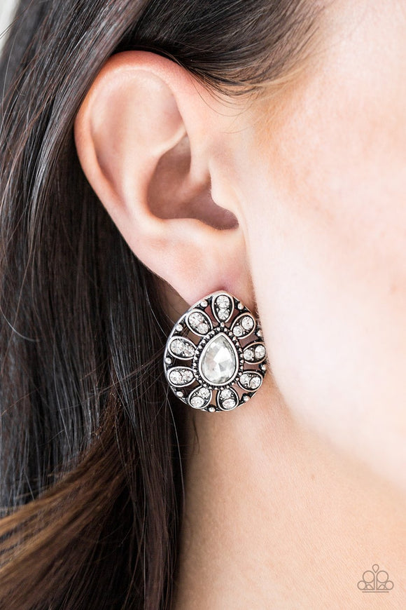 Paparazzi Treasure Retreat - White - Earrings
A teardrop silver frame is encrusted in glittery white rhinestones, creating a sparkling floral frame. Earring attaches to a standard post fitting.